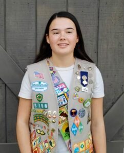 Shannon wearing Girl Scout vest with badges